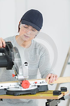 Young adult female woodworker cutting board in workshop