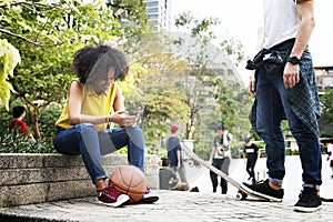 Young adult friends chilling at the park using smartphones and s