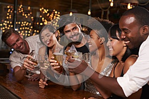 Young adult friends making a toast by the bar at a party