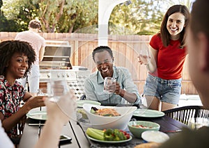 Young adult friends sitting outdoors and barbecuing photo