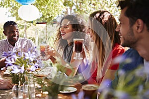 Young adult friends socialising at a table in a garden