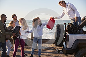 Young adult friends unloading backpacks from the back of car