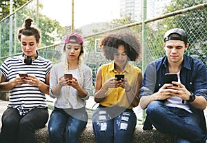 Young adult friends using smartphones together outdoors youth cu