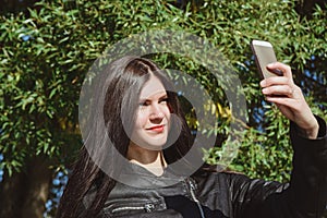 Young adult girl black leather jacket take selfie and looking at smartphone