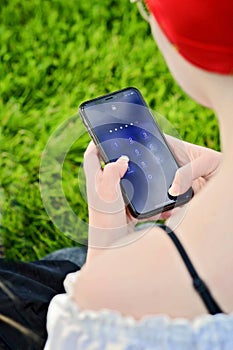 A young adult girl holding smartphone or cellphone in her hand typing a password or entering the passcode. A locker icon and