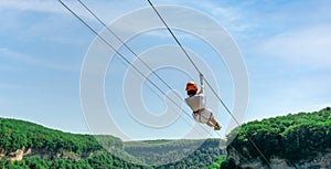 young adult girl rides a zipline in the mountains against a blue sky in thailand