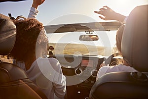 Young adult girlfriends driving with sunroof open, back view