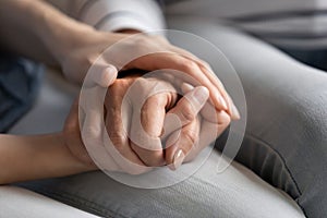 Millennial daughter holds hand of elderly mother express care closeup