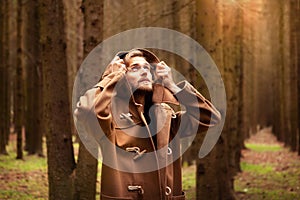 A young adult handsome man, with a mysterious look, in a dark wild forest.