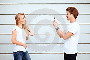 Young adult hipsters. boy and girl in white T-shirts smile and making selfie.