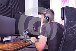 Young adult Hispanic male sitting in front of computer recording a podcast with microphone