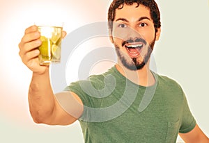 Young adult is holding a glass of drink made of lemon.