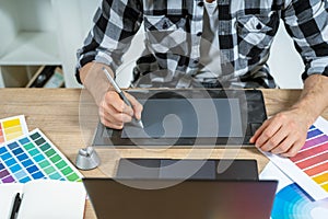Young adult illustrator working with graphic tablet in office