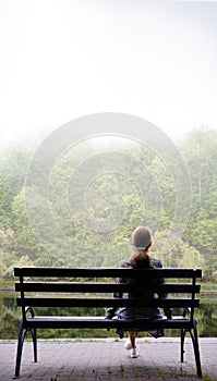 Lonely girl on a bench by the lake