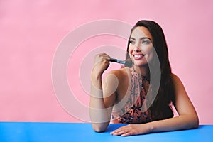 young adult latin beauty woman with makeup brush on studio background