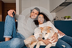 Young adult man, african american woman and dog watching tv at home