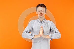 Young adult man closed eyes and prays.