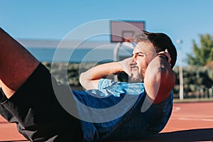 Young adult man doing an abs and obliques workout outdoors.Concept of overcoming, effort, reward, sacrifice and success