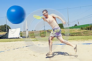 Young adult man plays tennis on the beach