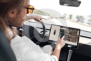 Young adult man sitting in car, using navigation system