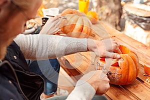 Young adult man and woman making jack-o-lantern pumpkin