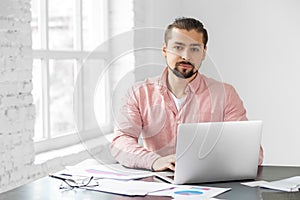 Young adult man working on a laptop. A man with a beard. Concept for business, corporation and making big money