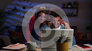 Young adult married couple doing a countdown to buy a real estate property using a laptop, they celebrate the purchase