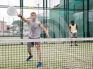 Young adult men playing doubles paddle tennis