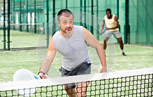 Young adult men playing doubles paddle tennis