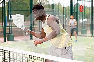 Young adult men playing doubles paddle tennis