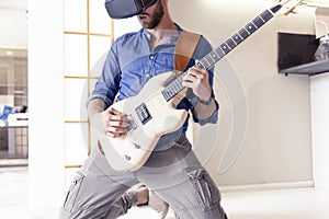 Young adult playing guitar at home using viewer for augmented re