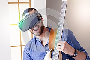 Young adult playing guitar at home using viewer for virtual real