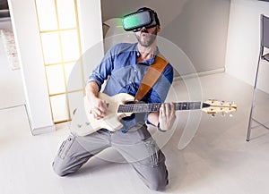 Young adult playing guitar at home using viewer for virtual real