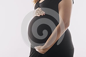 Young adult pregnant woman in white clothes touching big naked belly with hands. Showing shape. Pregnancy concept. Expectation