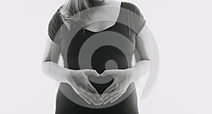 Young adult pregnant woman in white clothes touching big naked belly with hands. Showing shape. Pregnancy concept. Expectation