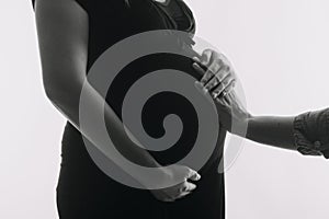 Young adult pregnant woman in white clothes touching big naked belly with hands. Showing shape. Pregnancy concept. Expectation