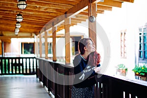 A young adult redhead brazilian posing in front of wood fences and smiling to the sky during the afternoon