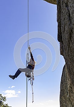 Young adult rock climber rappelling a granite wall in Torrelodones, Madrid. Extreme sports