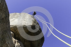 Young adult rock climber rappelling a granite wall in Torrelodones, Madrid. Extreme sports