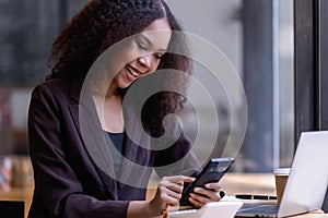 A young adult smiling holding smartphone, waiting for sms answer from online