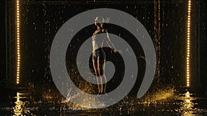 Young adult sporty woman performing skipping rope workout in sstudios in the rain. The rope strikes the surface of the