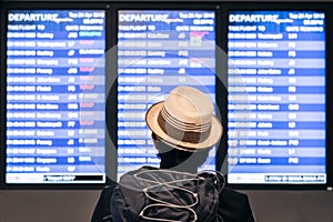 Young adult tourist traveler backpaker looking at airport flight schedule timetable on the screen photo