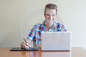 Young adult using computer and touch input tablet