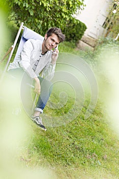 Young adult waiting on the phone sitting in the garden