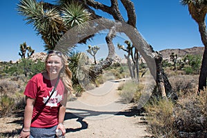 Young adult woman begins a hike in the large trees of Joshua Tree National Park