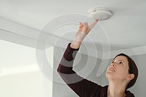 Young adult woman checking fire alarm