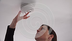 Young adult woman checking smoke alarm