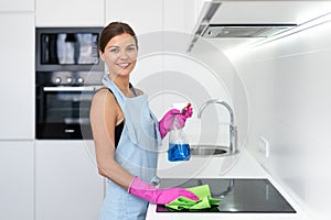 Young adult woman cleaning electric stove in kitchen