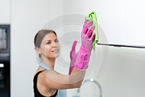 Young adult woman cleaning kitchen cabinet at home