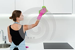 Young adult woman cleaning kitchen cabinet at home